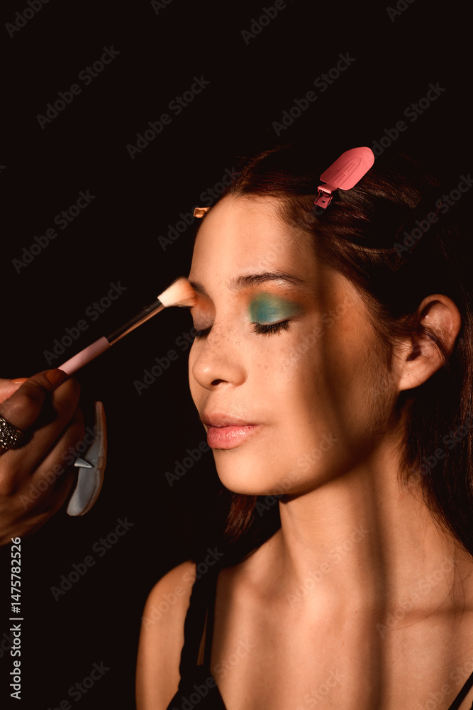 Obraz premium Woman being made up with eye shadow in a dark, elegant, baroque style environment