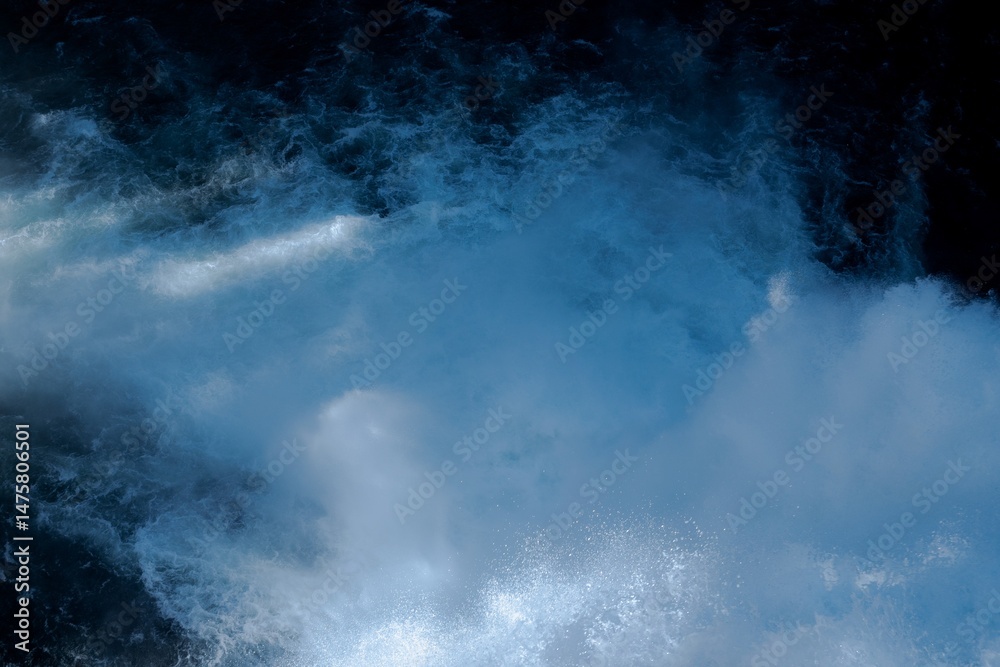 Obraz premium Close-up image of intense river rapids with foaming whitewater and deep blue currents. Dynamic and abstract natural texture showcasing the raw power and energy of flowing water.