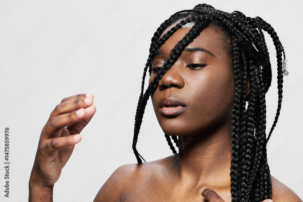 Fototapeta premium Young model with braided hair expressing confidence against a minimalist background, showcasing beauty, elegance, and self love in a professional photoshoot