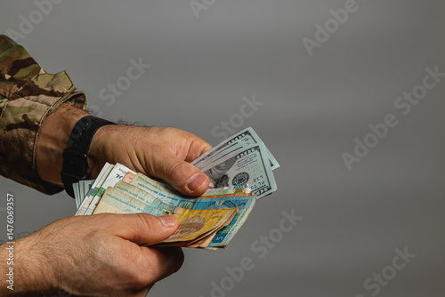 Soldiers counting different currencies in a neutral space