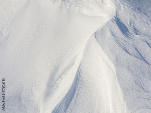 Snow texture. Wind sculpted patterns on snow surface. Wind in the tundra and in the mountains on the surface of the snow sculpts patterns and ridges (sastrugi). Arctic, Polar region. Winter background