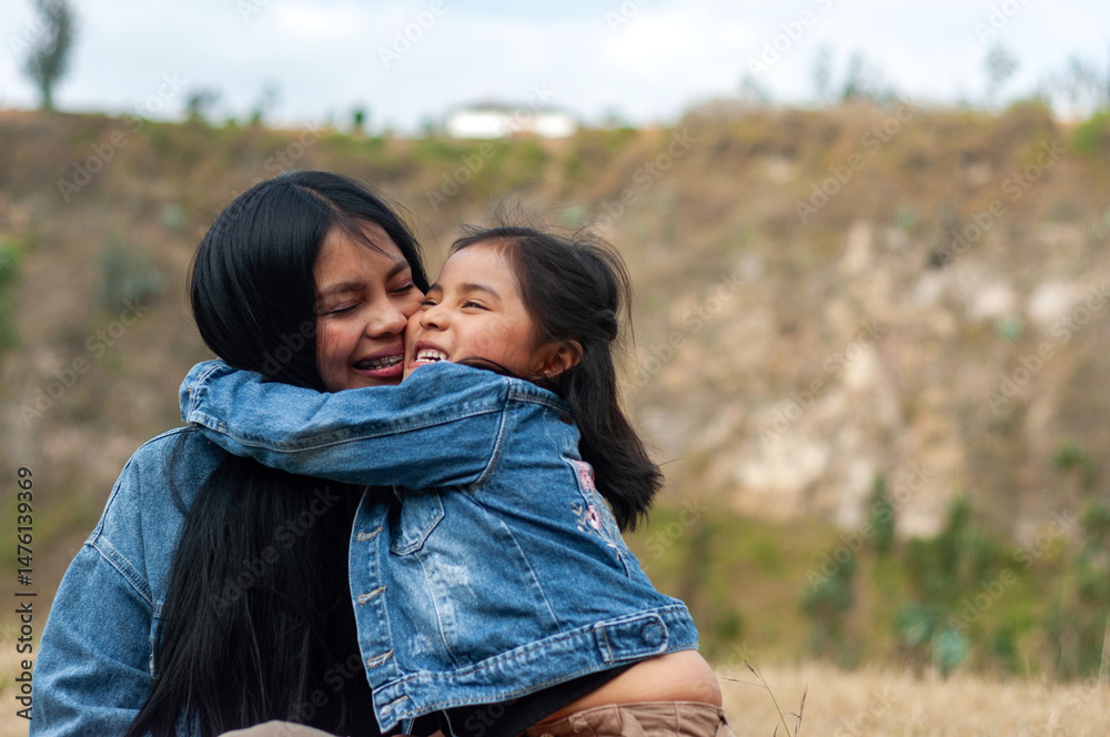 Fototapeta premium Latin american daughter embracing and kissing her mother outdoors