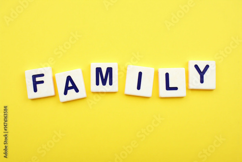 the word family spelled in scrabble tiles on a yellow background