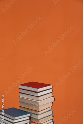 Stacks of educational books for learning on an orange background
