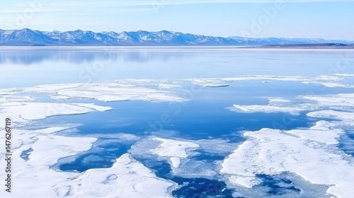 Lake Baikal in May, viewed from Olkhon Island, with small ice floes on the lake. Spring landscape with distant mountains and natural ice formations, capturing the changing season and spring travel vib