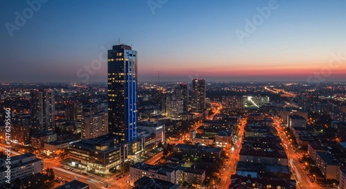 The tall and modern skyscraper, distinguished by its blue illuminated outline, stands as a focal point in the vibrant urban scene at dusk