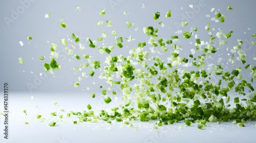 Chopped green onion pieces fall freely, creating a dynamic composition of light green hues and soft edges on a clean white backdrop, highlighting freshness