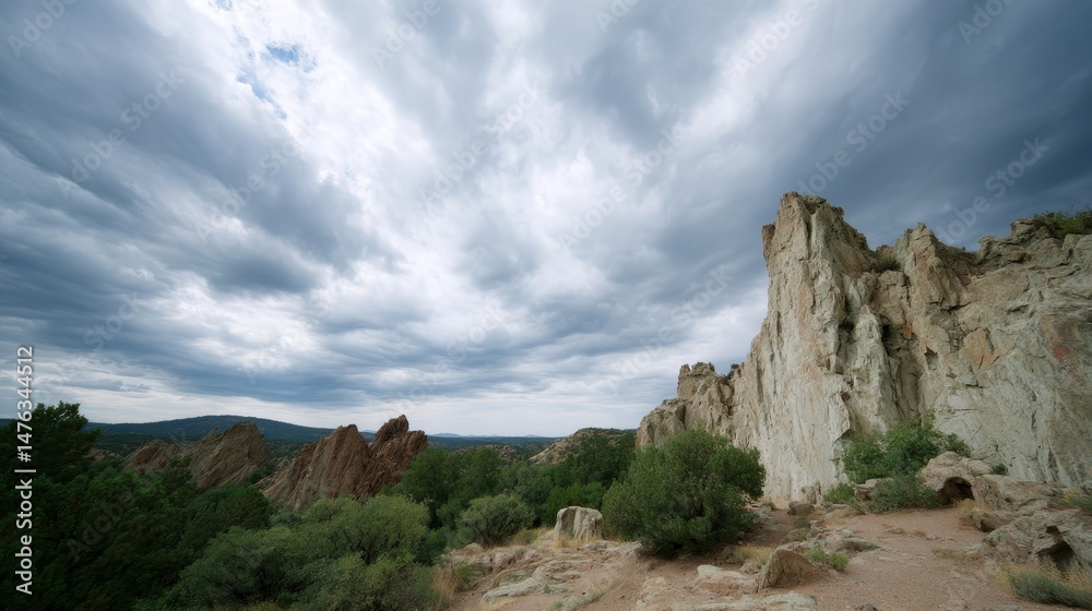 Fototapeta premium Jagged cliffs rise dramatically against a backdrop of swirling gray clouds, capturing the essence of a stormy day filled with powerful natural elements