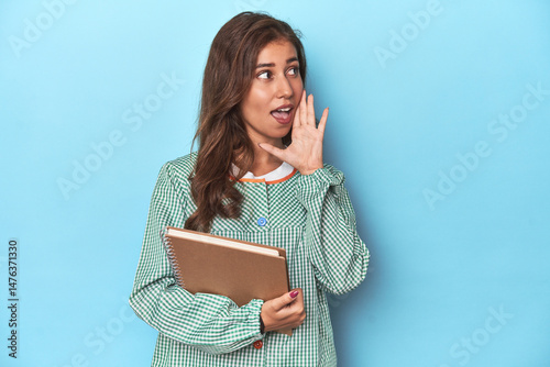Young teacher holding notebooks, imparting knowledge shouting and holding palm near opened mouth.