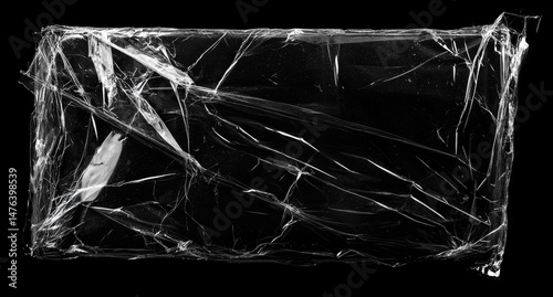 Cracked plastic wrap packaging.  A rectangular piece of transparent plastic wrap, torn and wrinkled, against a black background