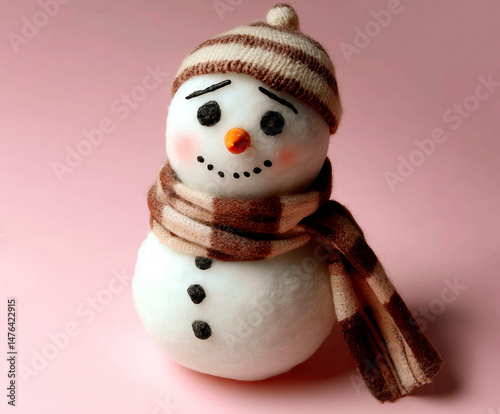 A cute handmade snowman with a striped hat and cozy scarf stands against a soft pink background, featuring a warm and charming winter theme. 