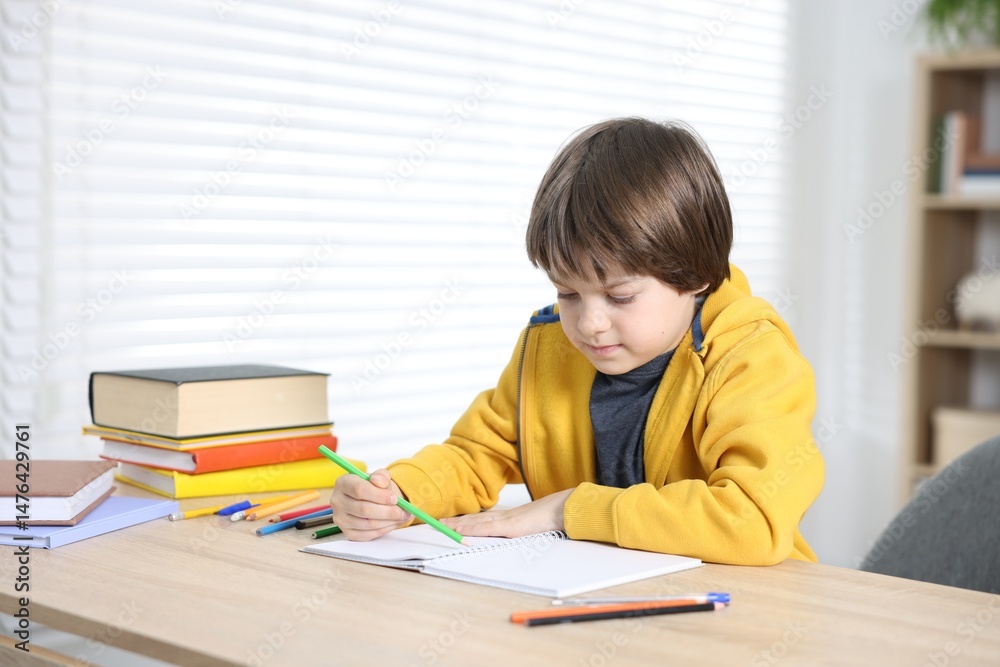 Cute little boy doing homework at table indoors Cute little boy doing homework at table indoors