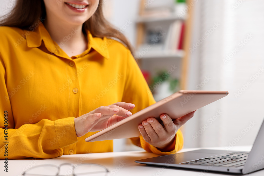 Fototapeta premium Woman using modern tablet at desk indoors, closeup. Space for text