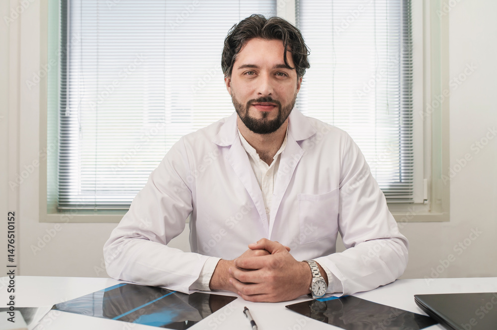 Fototapeta premium Young specialist doctor portrait on background of doctor's office in hospital. professional healthcare, intern, male doctor. Family doctor, therapist