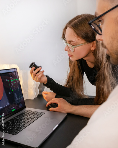 Two focused individuals, a South Asian male and a Caucasian female, analyze complex algorithms, coding fever, Ada Lovelace Day ingenuity, 3D printer, 3D printing photo