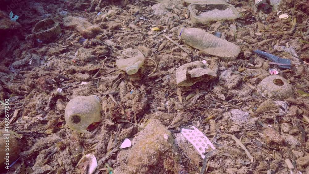 Camera moving backwards and up showing view on massive pollution of seabed polluted with plastic and other debris, Slow motion. Plastic pollution of the Ocean