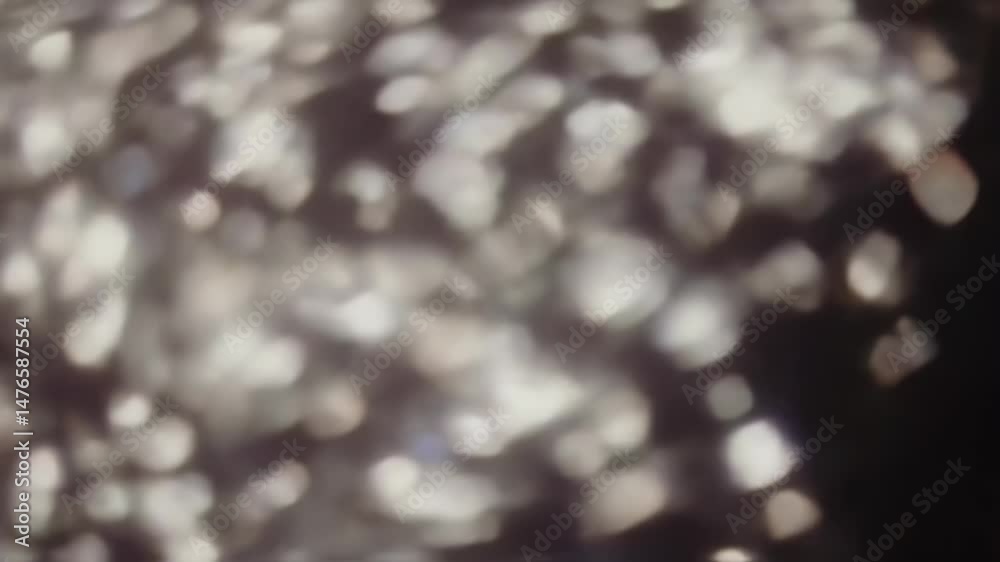 Abstract background of shimmering, irregular white bokeh lights and soft, blurred shapes against a dark backdrop, creating a dreamy, ethereal, and atmospheric visual texture for creative projects.