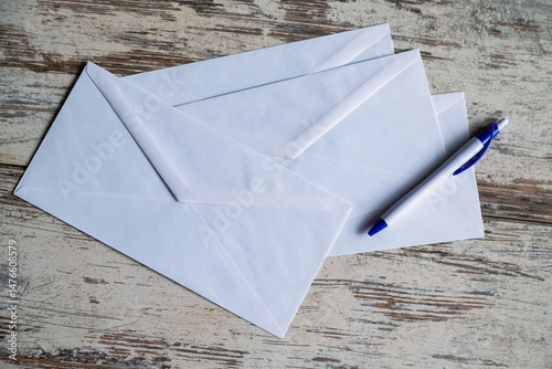 White mailing envelopes and a fountain pen on a wooden table reflect classic style and nostalgia for paper correspondence. For themes related to retro design, epistolary culture, and romantic letters.