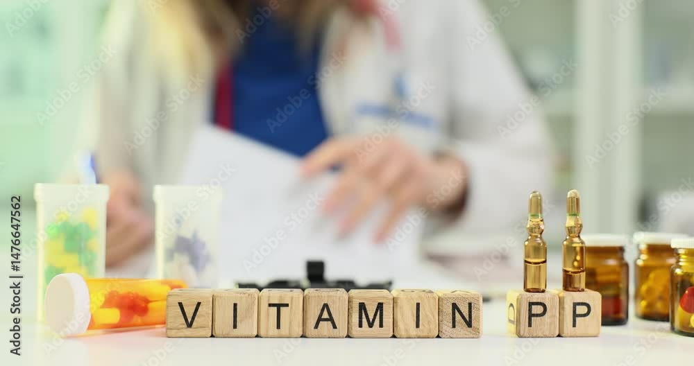 Physician writes prescription for Vitamin PP on cubes. Ampoules filled with liquid medication and blister pack of multicolored pills arranged on desk