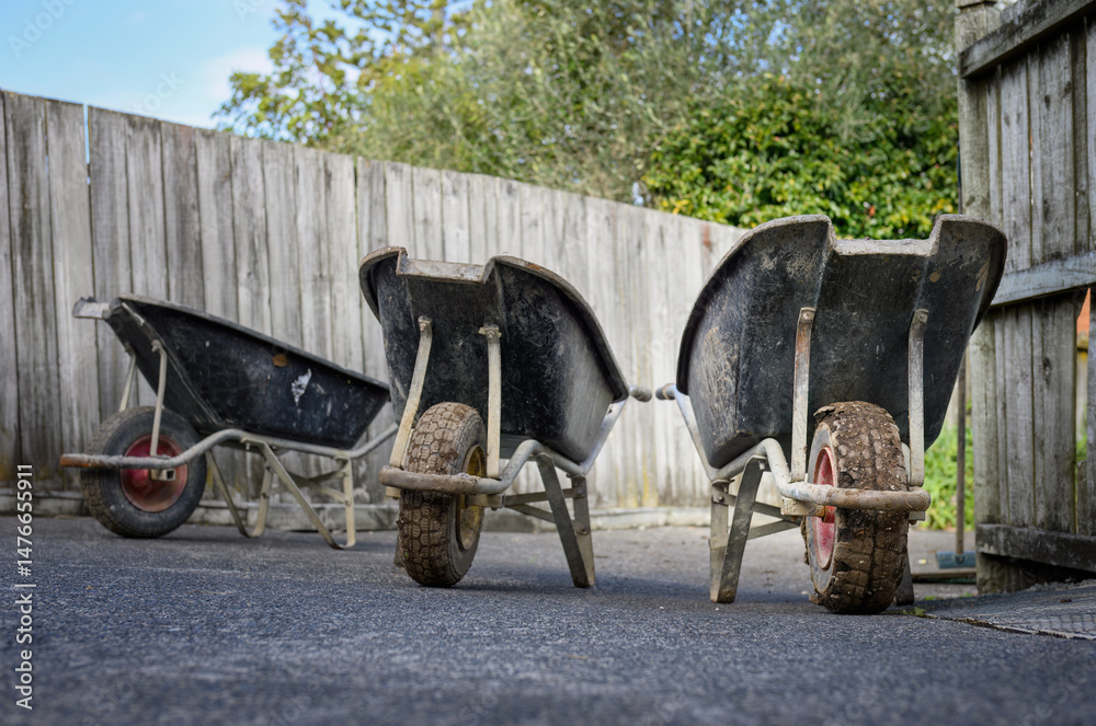 Fototapeta premium Three empty wheelbarrows on the driveway. House construction work. Auckland.