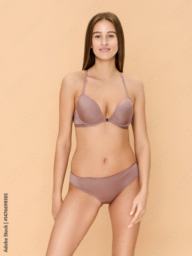 Fototapeta premium Girl model in lingerie posing on beige studio background.