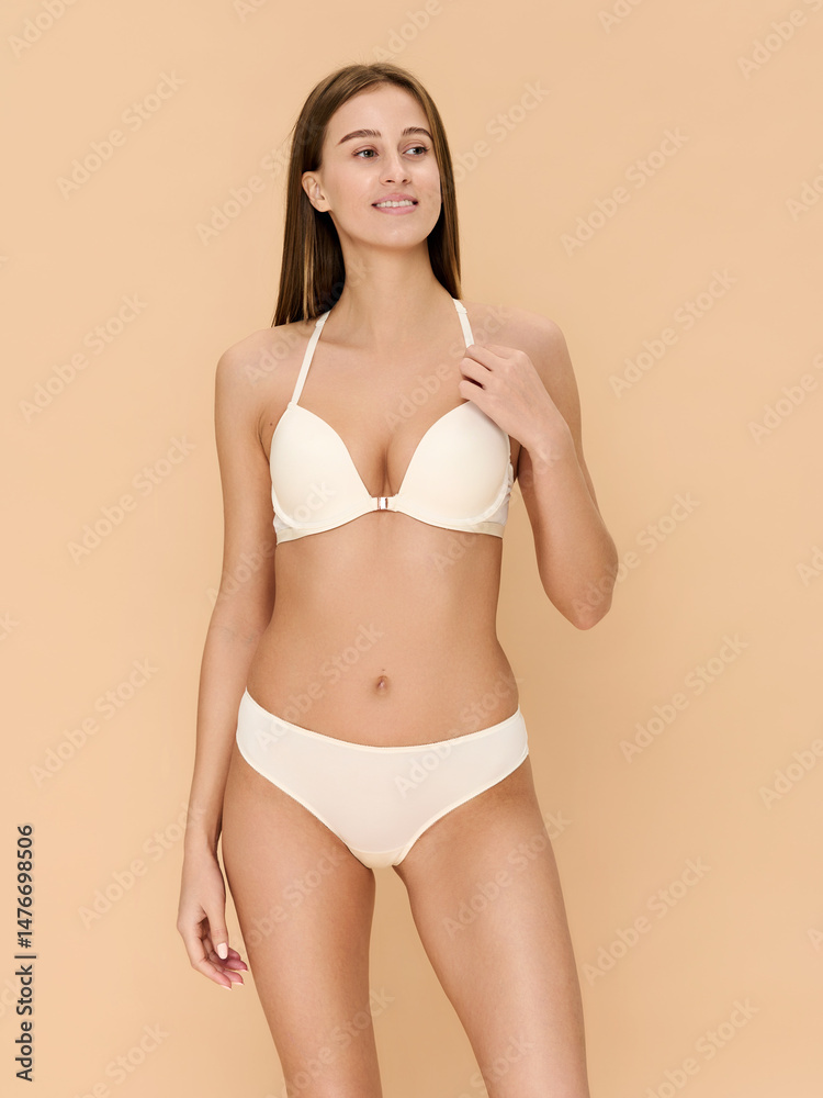 Obraz premium Girl model in lingerie posing on beige studio background.