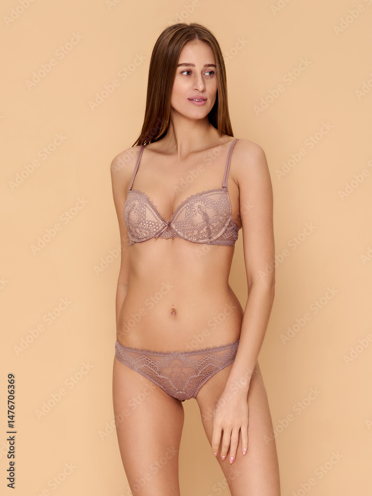 Fototapeta premium Girl model in lingerie posing on beige studio background.