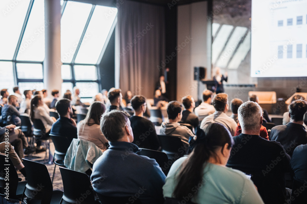 Obraz premium Speaker giving a talk in conference hall at business event. Rear view of unrecognizable people in audience at the conference hall. Business and entrepreneurship concept