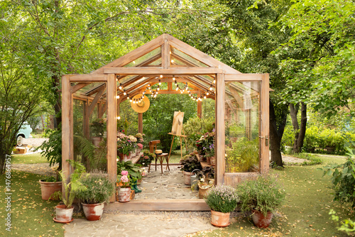 Foto Interior of a wooden greenhouse with furniture, plants and flowers in pots at backyard