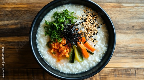 Korean cold rice porridge Juk served pickled vegetables normal view of warm rice porridge with soft textured grains garnished with pickled vegetables against a simple wooden surface photo