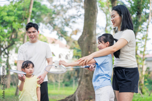 Family plays badminton in a park during a sunny afternoon with laughter and joy