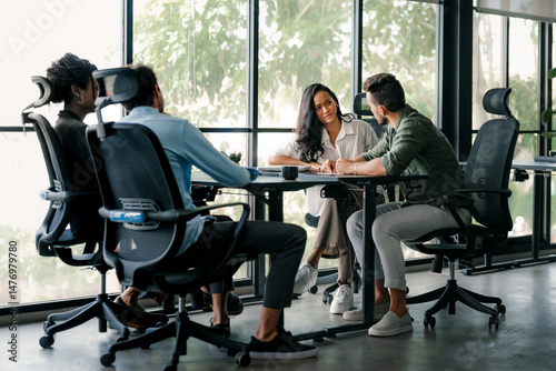 Group of young multi-ethnic startup business team collaborating on project in modern office
