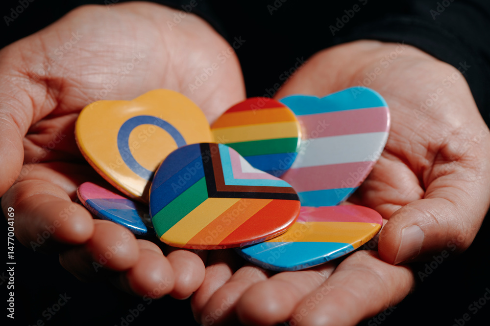Fototapeta premium man holding badges with different LGBTQ flags