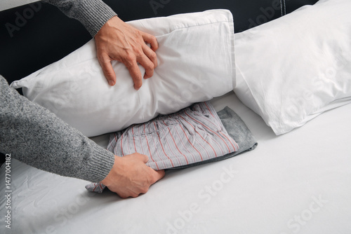 man places his pajamas under his pillow