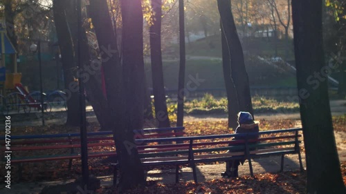 Elderly old woman rests on a bench in the rays of the autumn sun