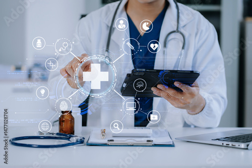 Doctor working on laptop and tablet and medical on clipboard on desk, electronics medical record system EMRs concept.