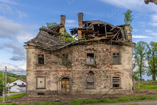 Ruined house with collapsed roof and broken windows is slowly decaying