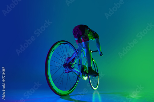 Εκτύπωση καμβά Back view dynamic image of man, cyclist in motion on bicycle, training against blue background with green neon light