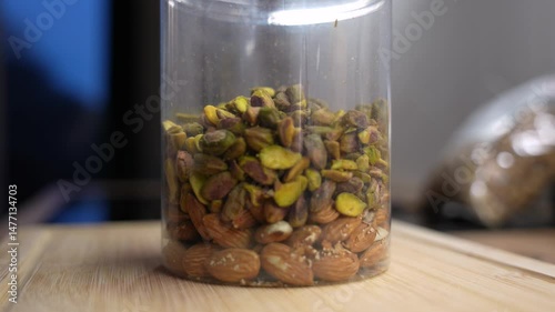Macro shot of mixed nuts filling plastic jar. Healthy vegan snack