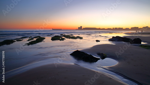 The beach at sunset in Les Sables d'Olonne, Vendee, France, with the jetty and the lighthouse in the background