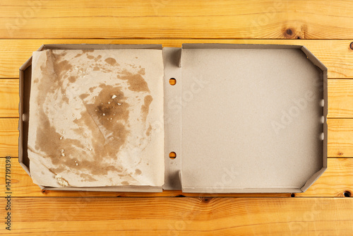 Pizza box with breadcrumbs on natural wooden table flat lay view