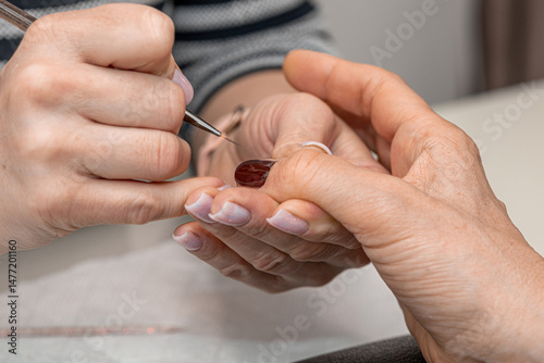 Nail care procedure in a beauty salon. Female hands and tools for manicure, process of performing manicure in beauty salon. Concept spa body care. Gloved hands of a skilled manicurist cutting cuticles