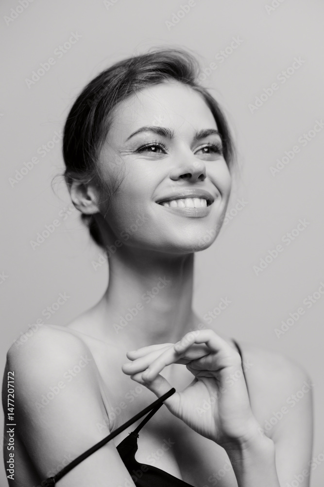 Obraz premium Smiling young woman with natural makeup forming a heart shape with her hands, expressing joy and positivity. Emotional and intimate portrait concept.