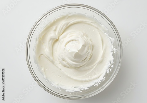 Overhead view of whipped cream in a clear glass bowl