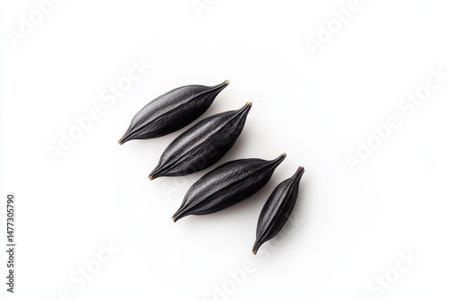 Dark, oblong seeds arranged in a slight diagonal pattern against a plain white background