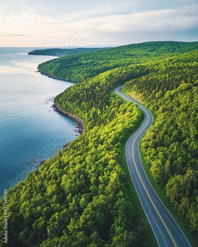 Aerial view of winding coastal road through lush green forest near ocean in Cape Breton Nova Scotia Canada travel destination landscape