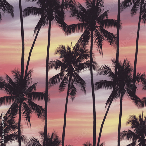 Silhouette palm trees pattern at sunset with pink and yellow summer sky