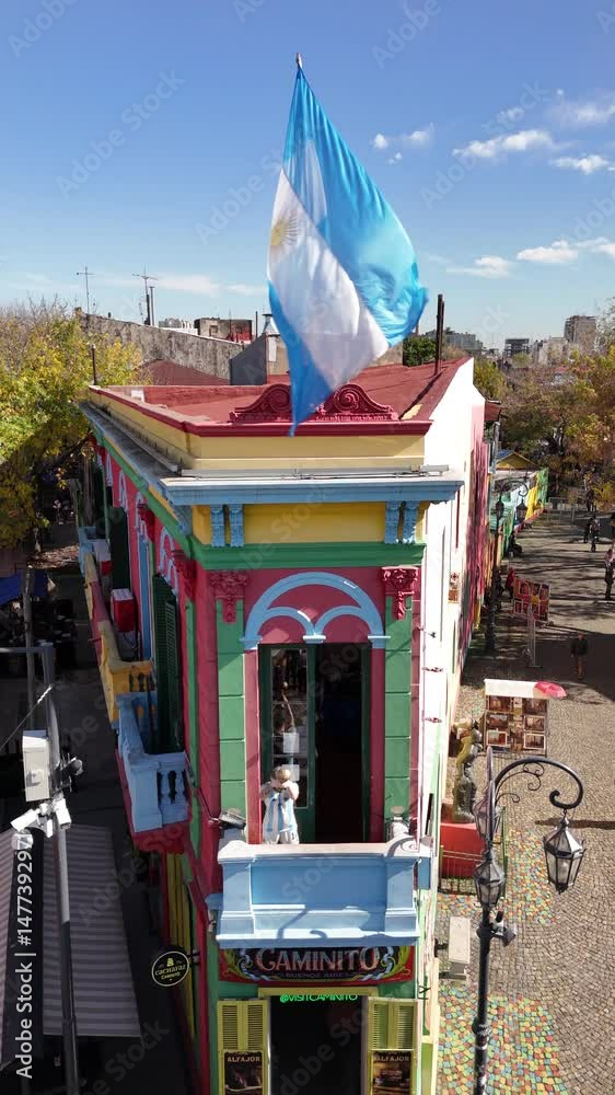 Traditional Caminito passage with tourists and panoramic view of the city from La Boca neighborhood. Aerial camera rises from the street