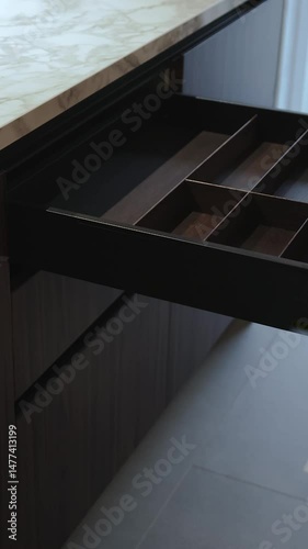 Close-up of a woman's hand opening an empty kitchen drawer. Stylish kitchen with marble countertops. Vertical video