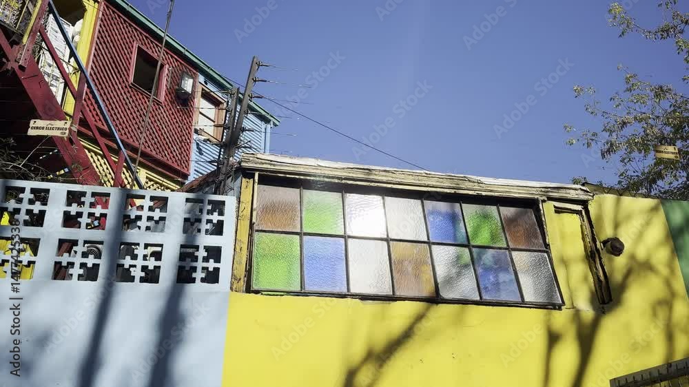 Traditional Caminito passage with tourists and panoramic view of the city from La Boca neighborhood. Aerial camera rises from the street